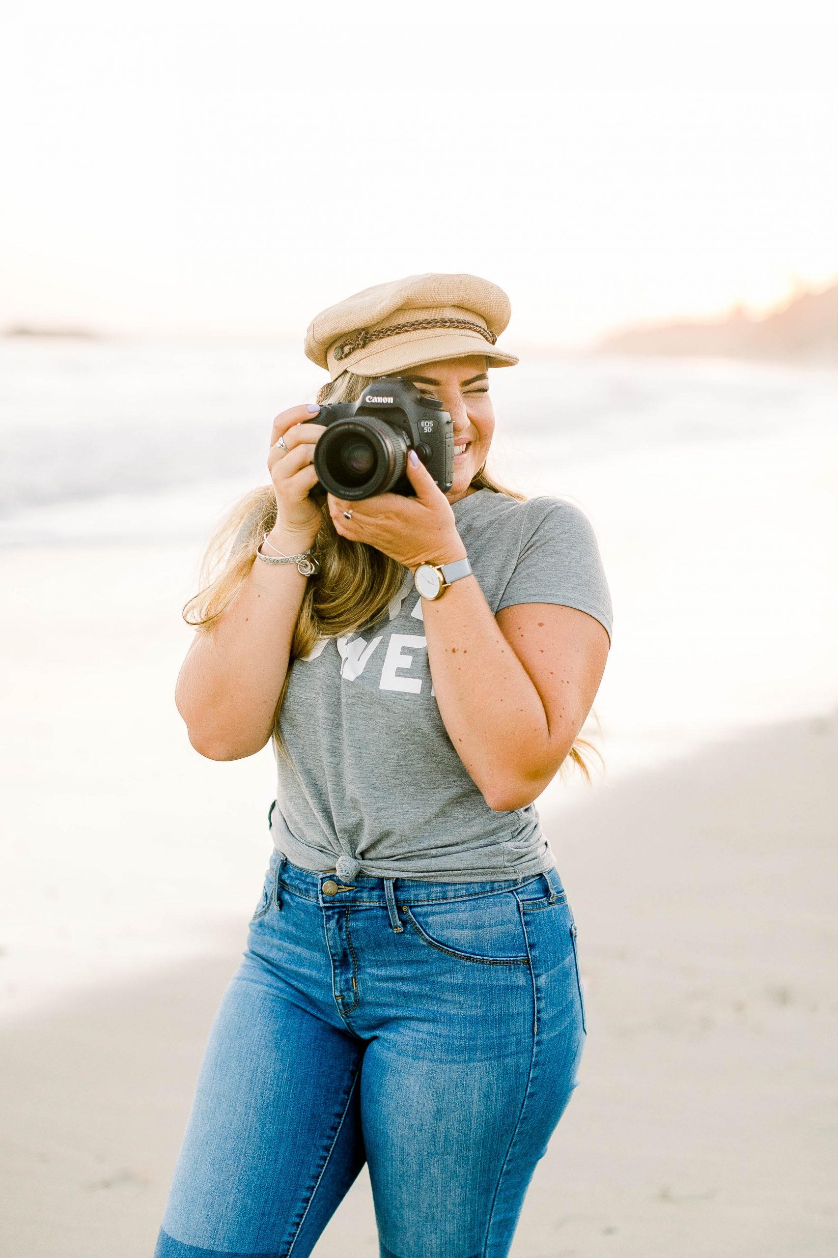 Woman holding camera up to her eye at beach