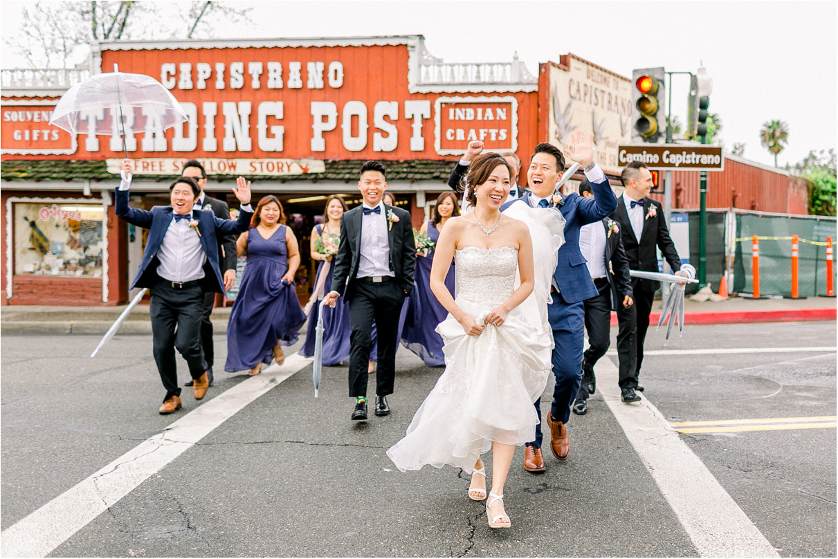 entire wedding party walking across the street smiling laughing and having fun