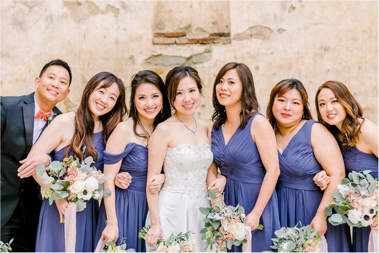 Bride with her bridesmaids all smiling at the camera