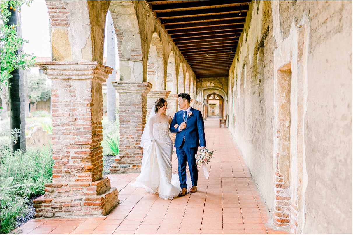 wedding couple walking towards camera at a mission