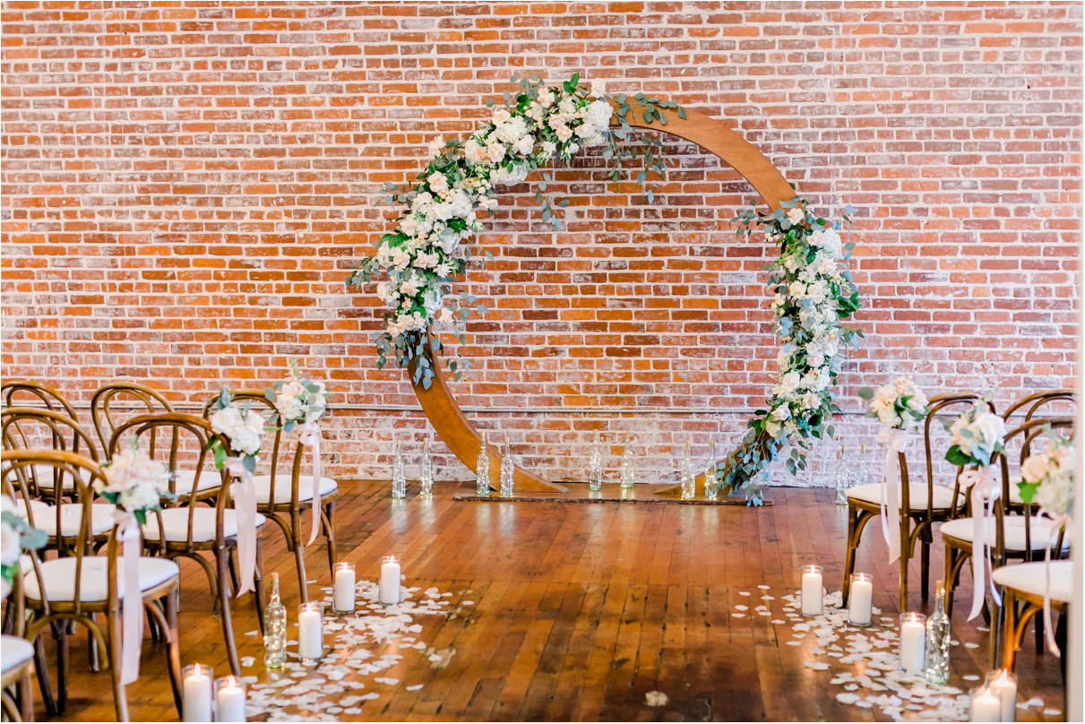 wedding ceremony arch with flowers against brick wall