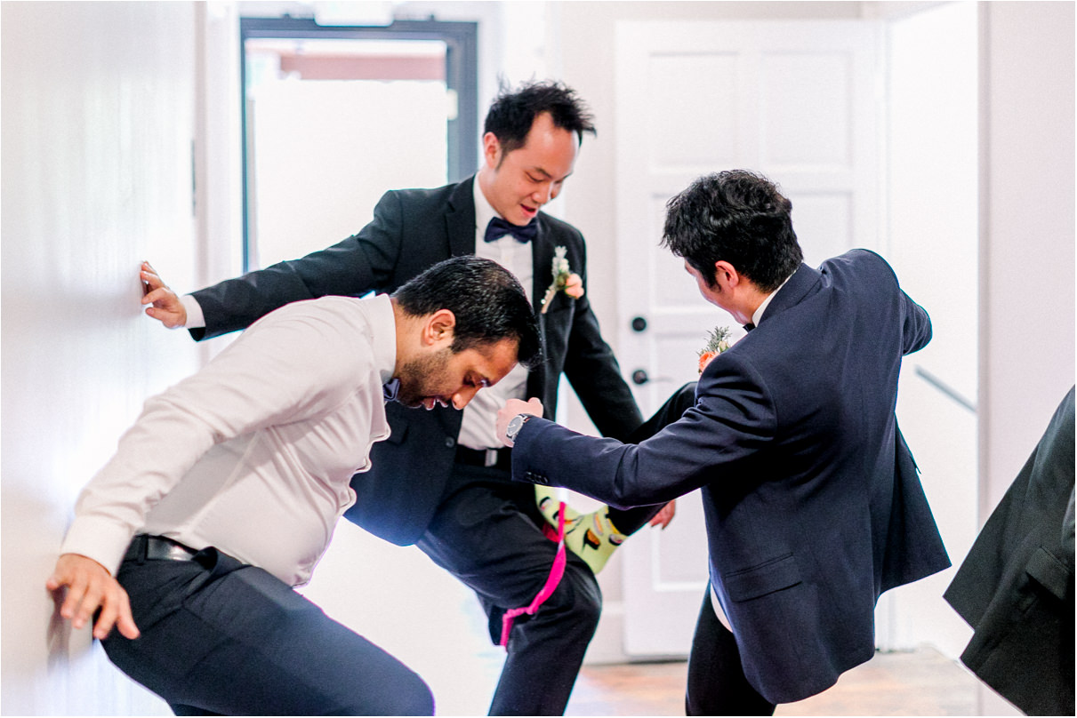 three men trying to pull pink underwear over their black suits
