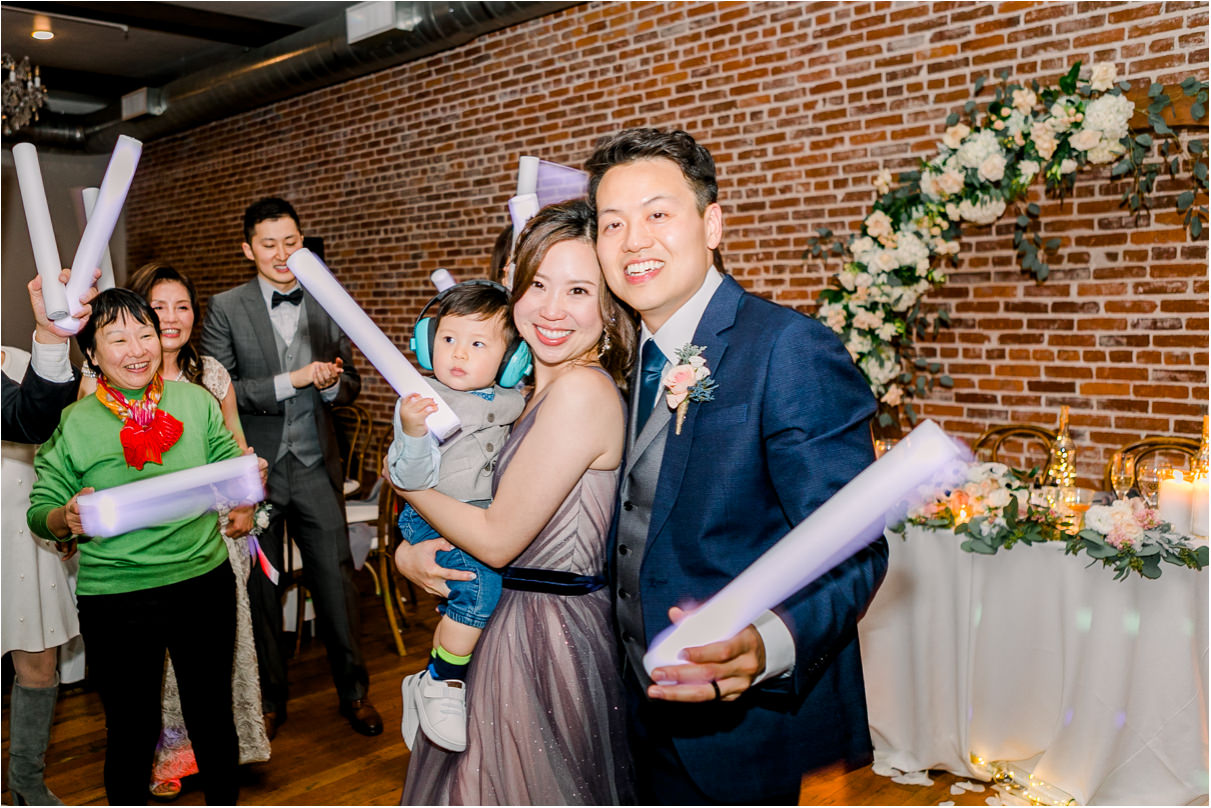 bride and groom holding guests baby and glow sticks