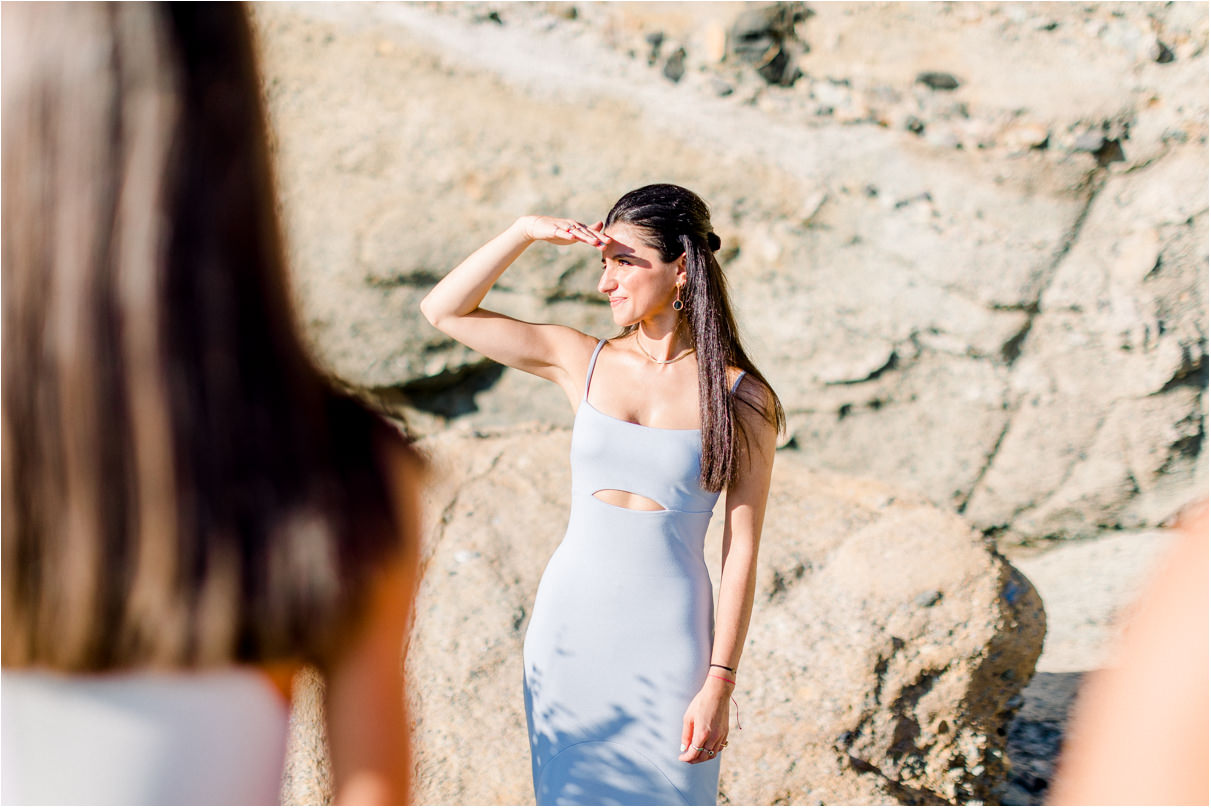 Woman holding her hand to her face shading her eyes from the sun in fancy dress at the beach