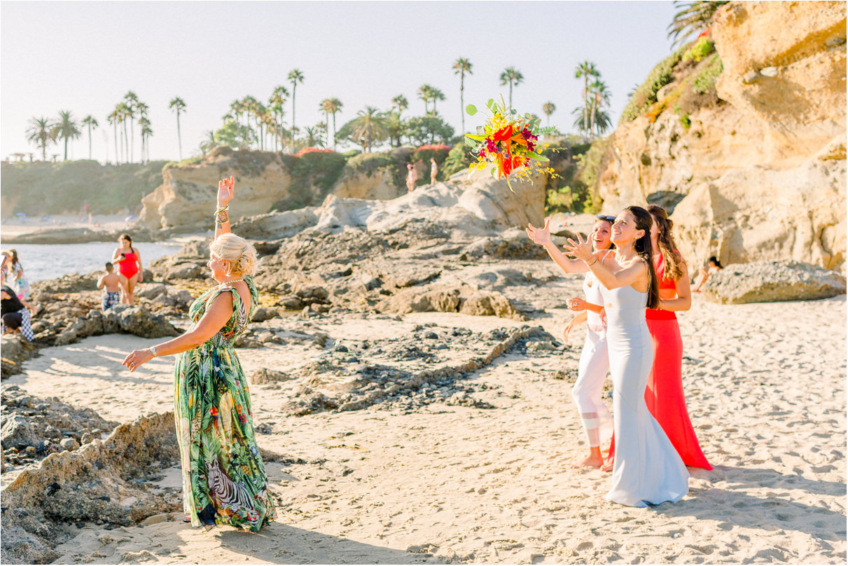 Bride throwing bouquet to three daughters behind her at the beach