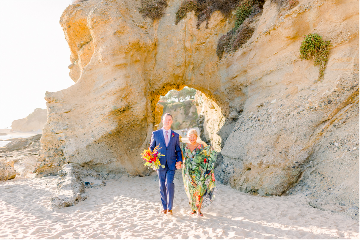 Couple in colorful clothes walking towards the camera on sandy beach