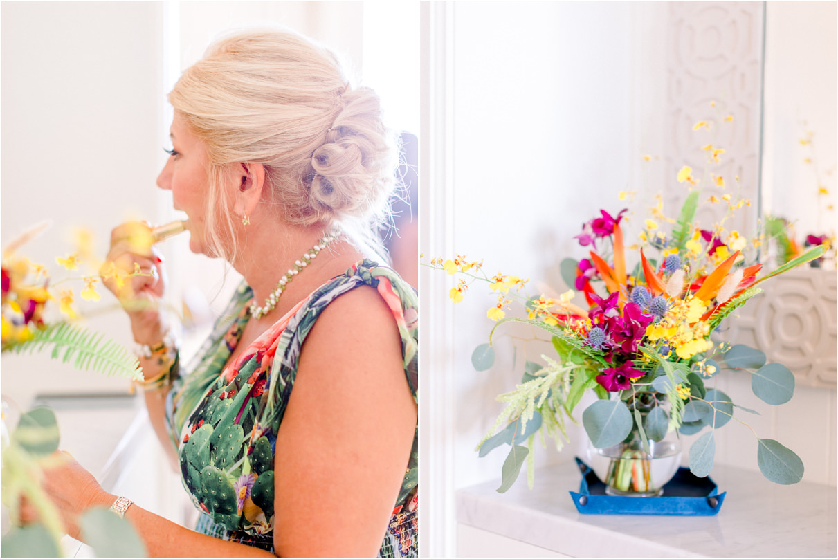 Bride putting on lipstick in hotel with flower bouquet