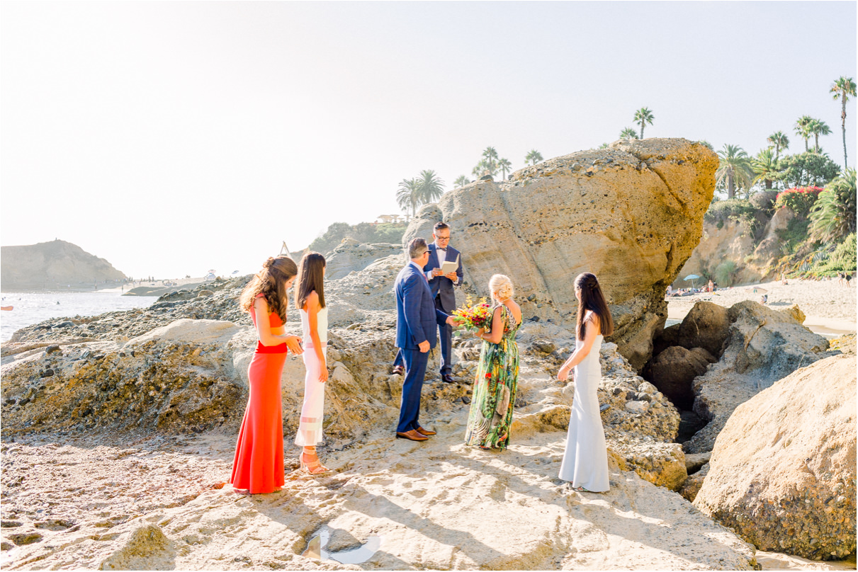 Six people on rocks by the beach for small wedding ceremony