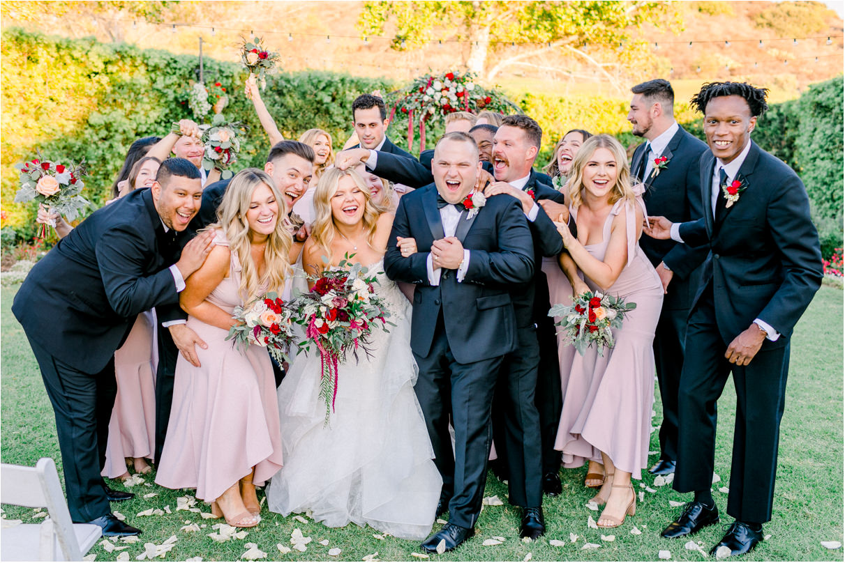 Wedding party giving bride and groom group hug and noogie