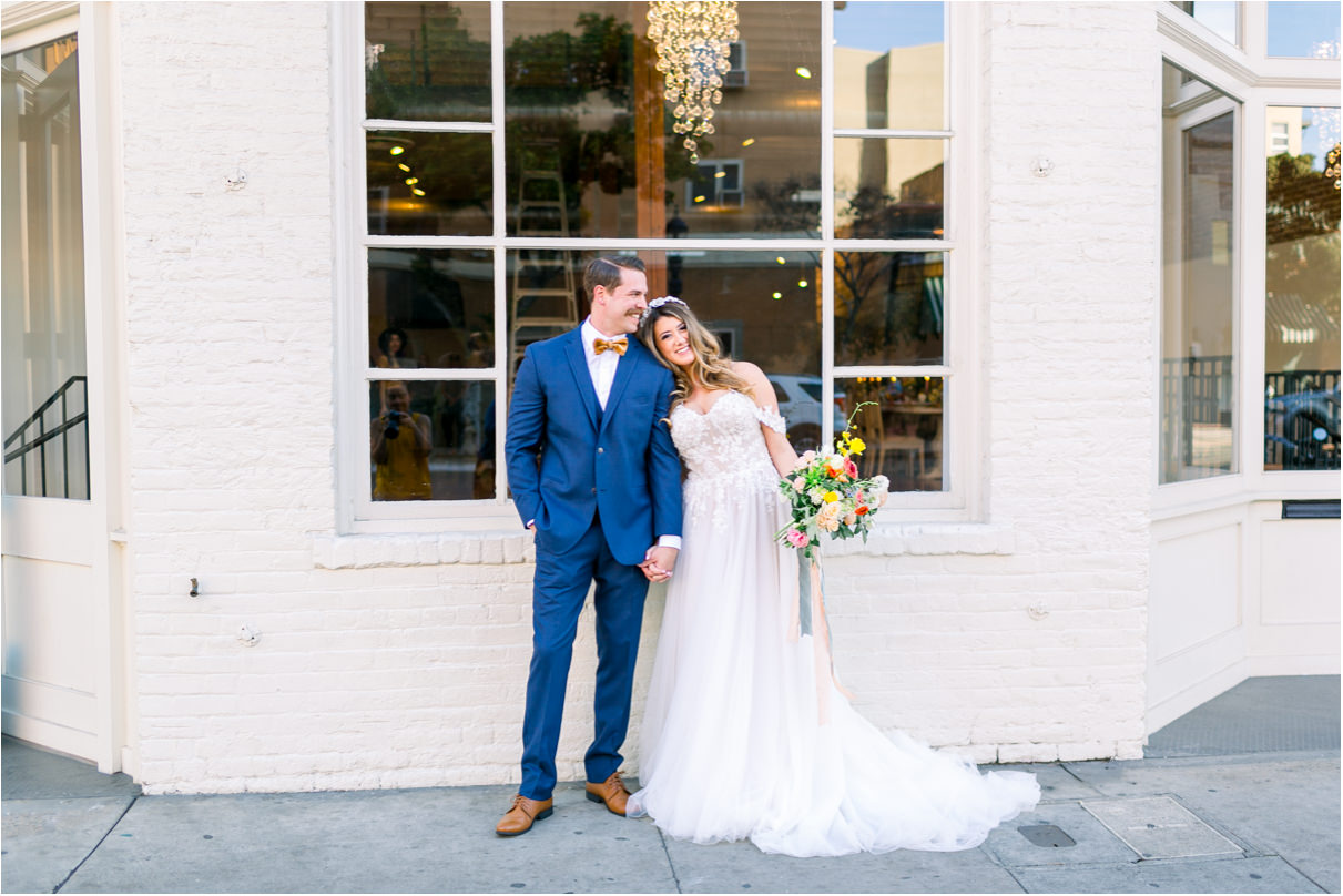 Man and woman getting married outside of white brick building