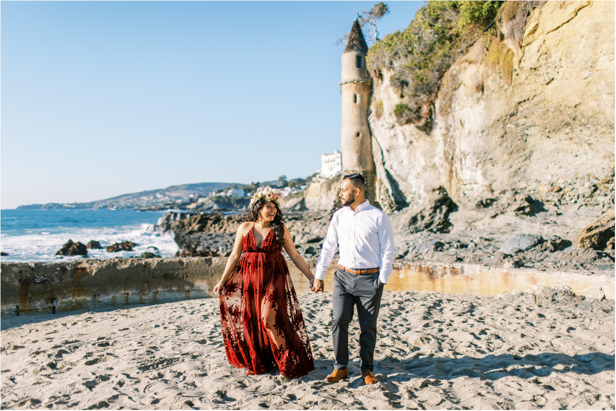 Couple walking towards camera at beach with castle tower