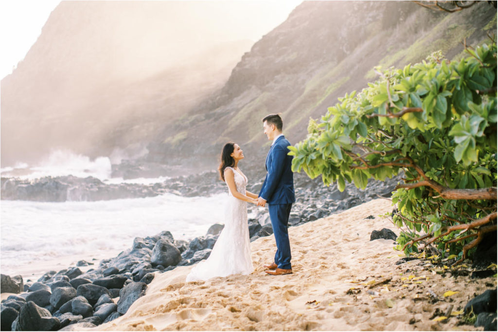wedding couple holding hands facing each other at beach