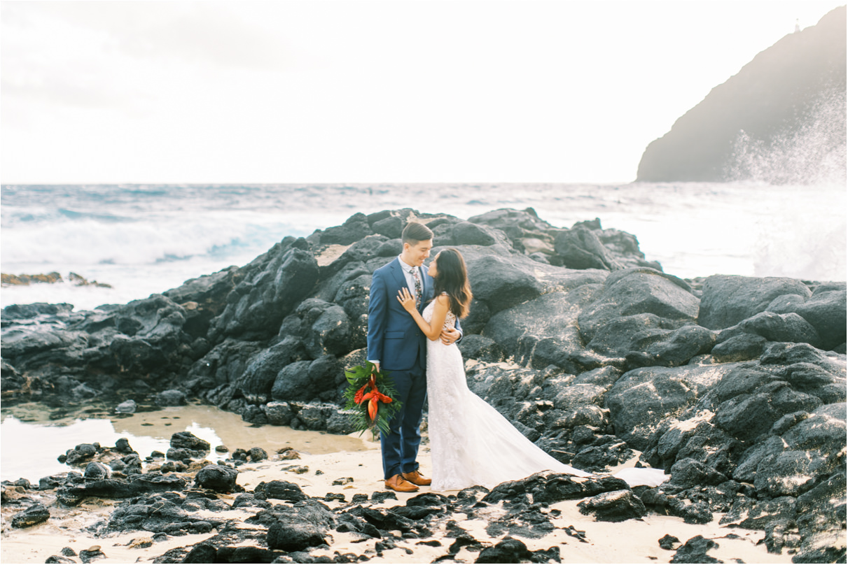 wedding couple at rocky beach with waves crashing behind them