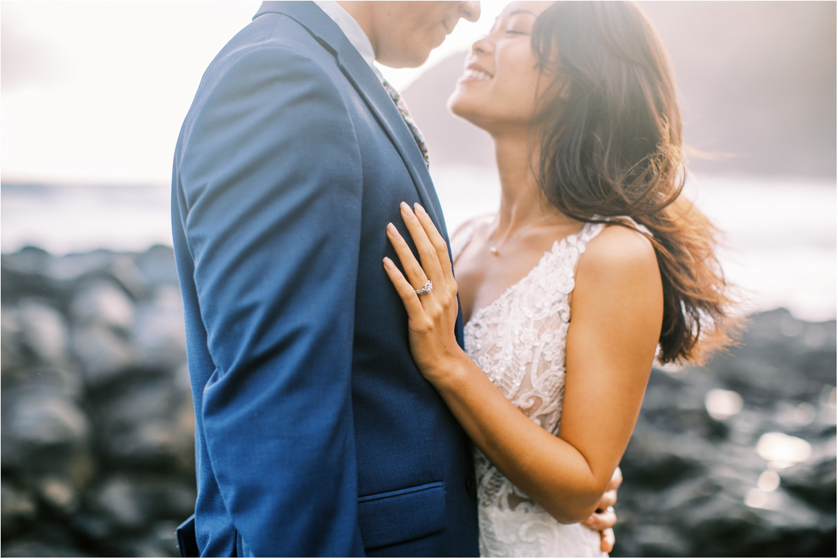 bride and groom looking into each other eyes at beach with wind in her hair