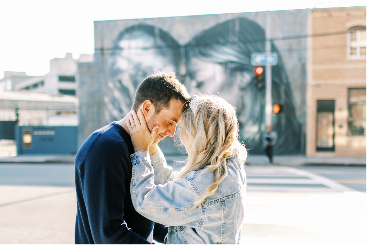 couple putting heads together in front of black and white mural in los angeles