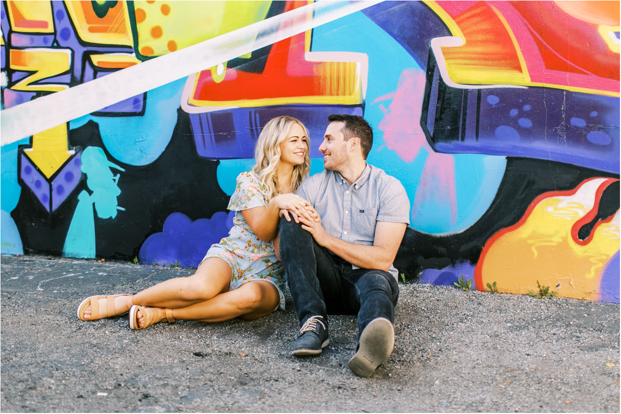 couple sitting in front of very loud graffiti wall