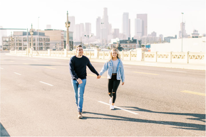couple holding hands walking across los angeles bridge