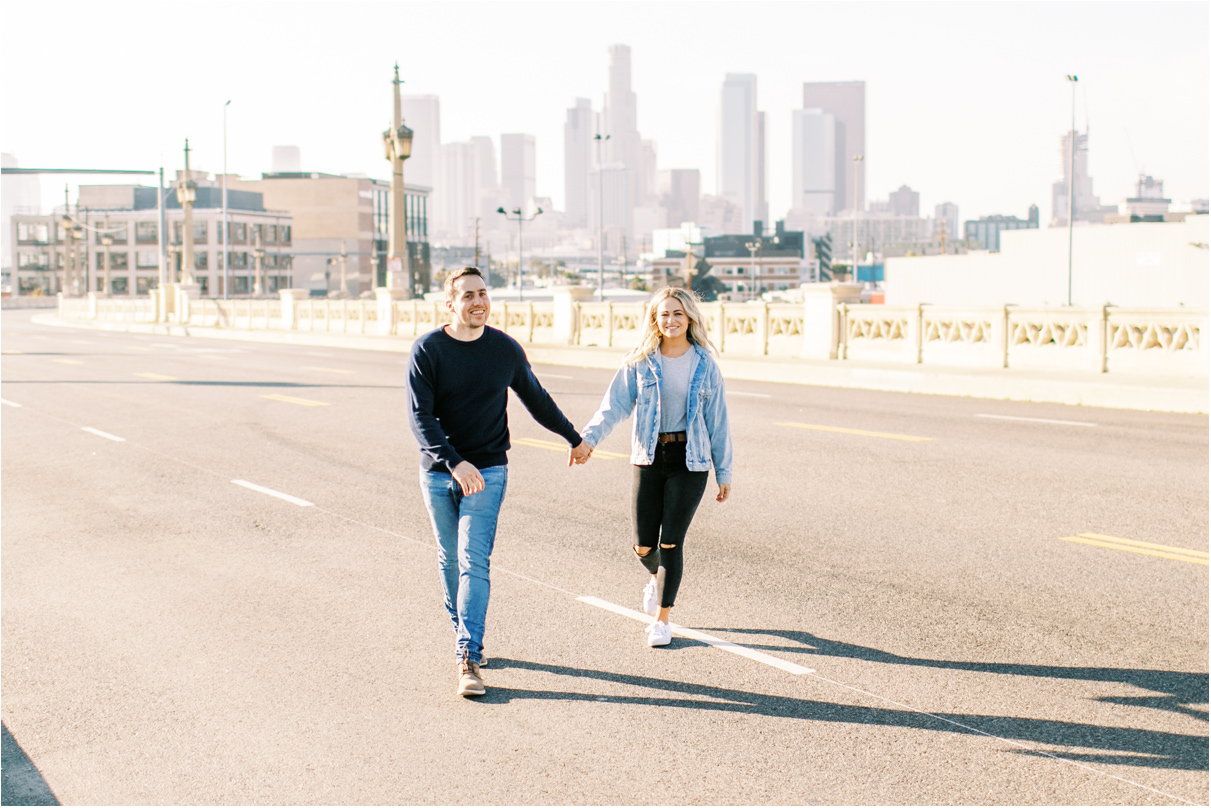 couple holding hands walking across los angeles bridge