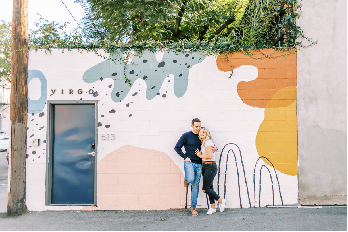 Couple cuddling in front of mural wall in los angeles