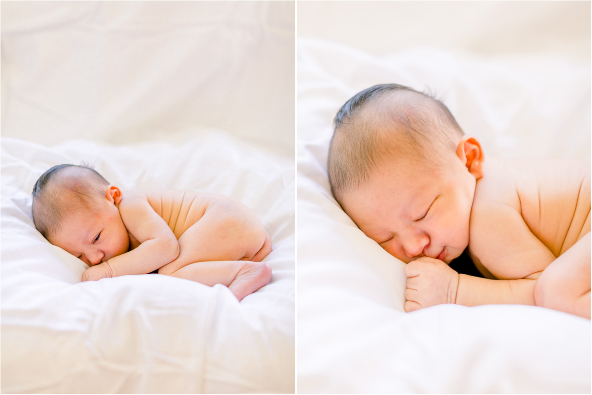 Naked baby boy laying curled up on white sheet sleeping