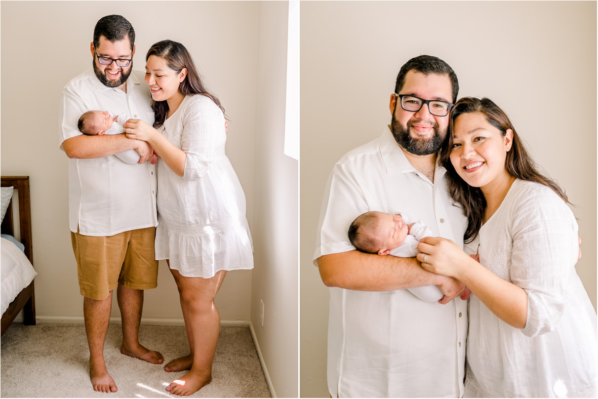 Parents standing against wall holding baby and smiling at the camera