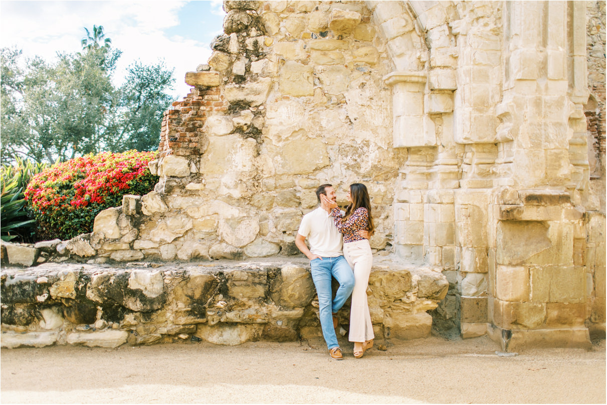 Couple holding each other while sitting on old mission ruins