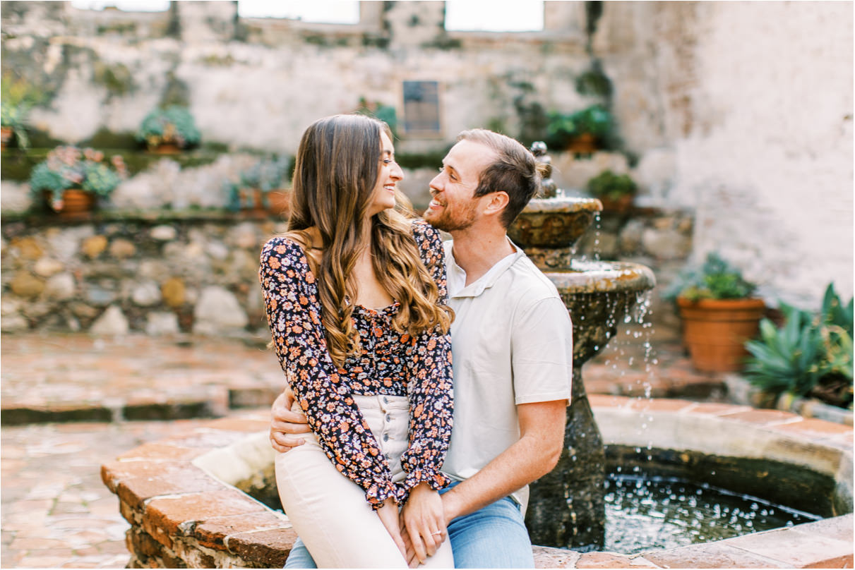 Closeup of couple sitting near water fountain smiling at each other