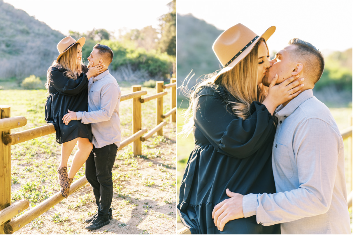 Couple kissing while woman sits on wooden fence