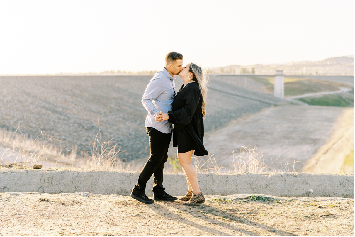 Couple kissing at sunset with large riverbed behind them