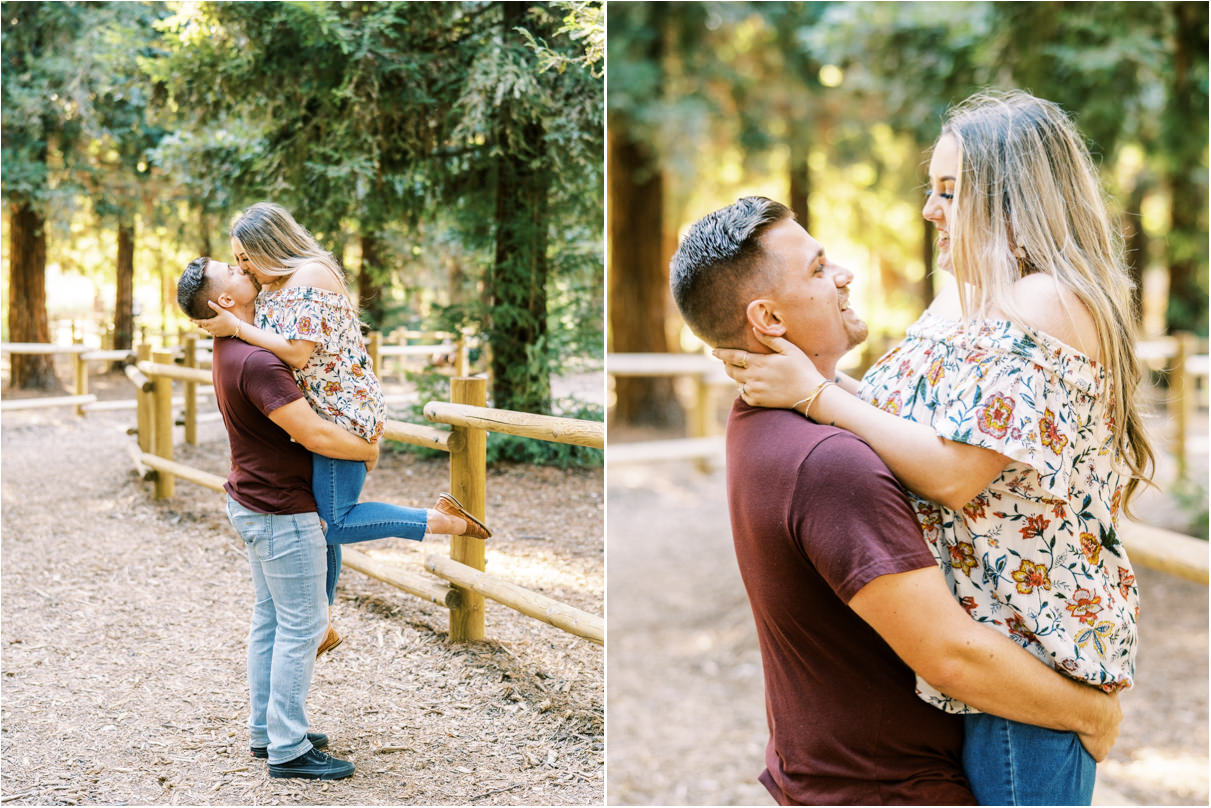 Man holding women up as they kiss and smile at each other in forest
