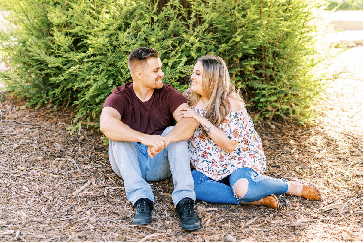Couple sitting on forest floor smiling at each other