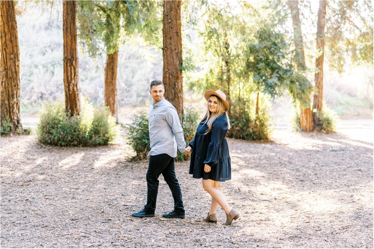 Couple holding hands and walking away from camera in a forest