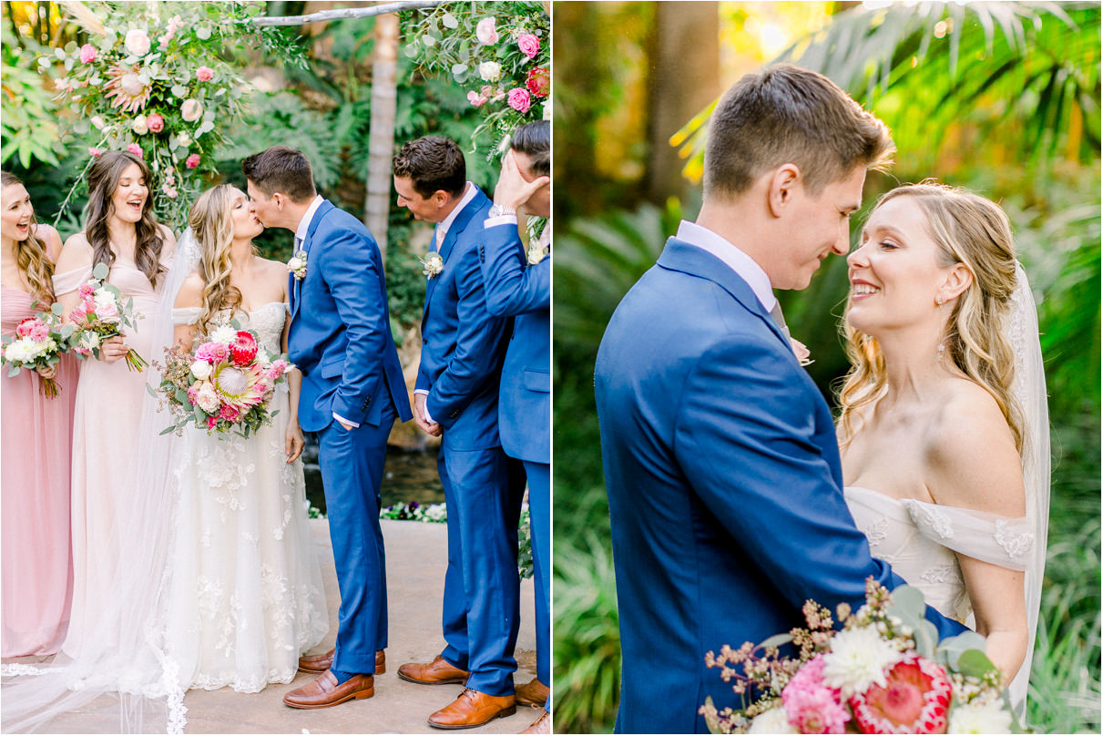 Bride and groom kissing with wedding party cheering next to them