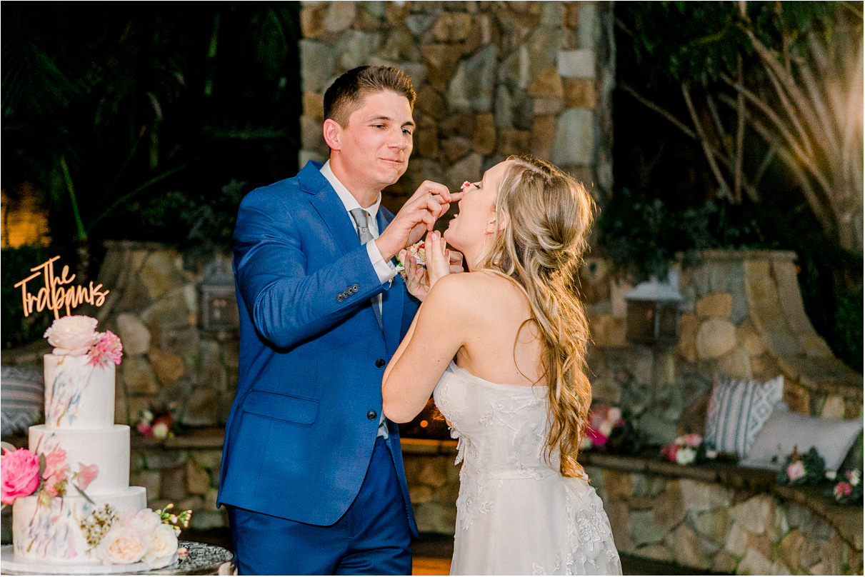 Groom putting cake on brides face during reception