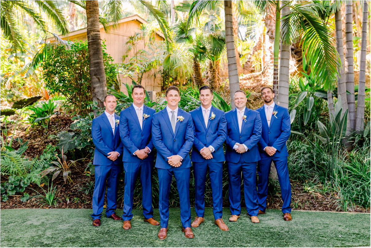 Groomsmen in flying V formation all smiling at the camera in blue suits