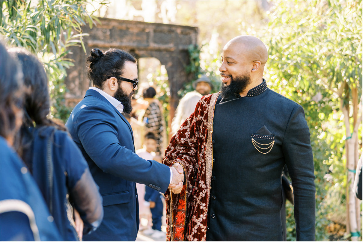 Candid photo of groom greeting friend before wedding ceremony