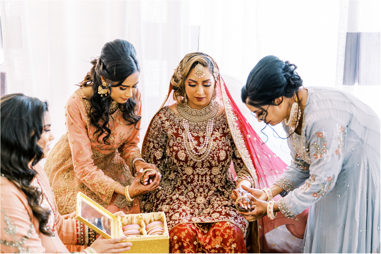 Pakistani bride with family helping put on her bangles