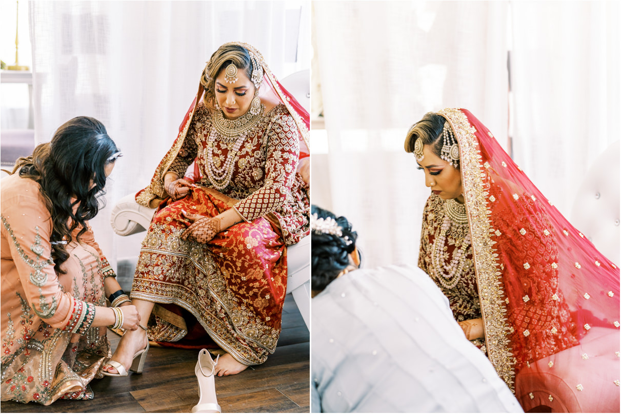 Pakistani bride sitting in white room as family helps her put on shoes