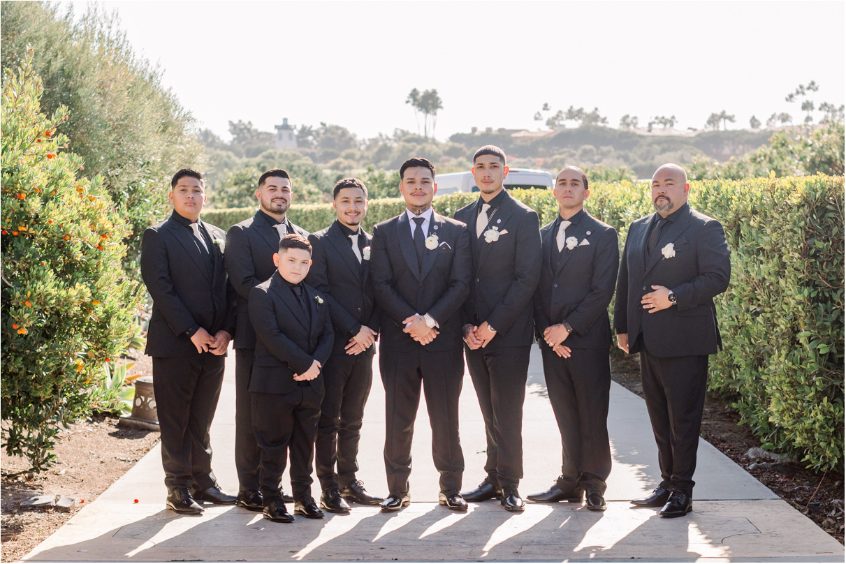 Groom with groomsmen in black tux standing side by side