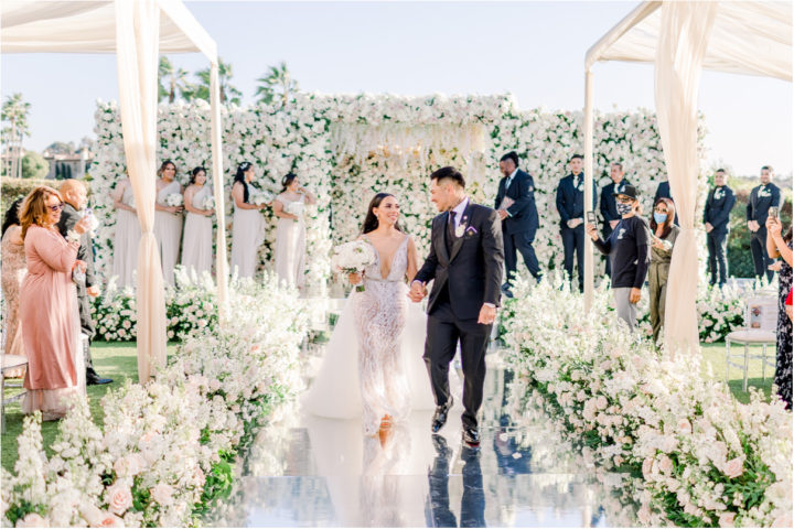 Bride and groom walking down aisle after saying I do smiling at each other