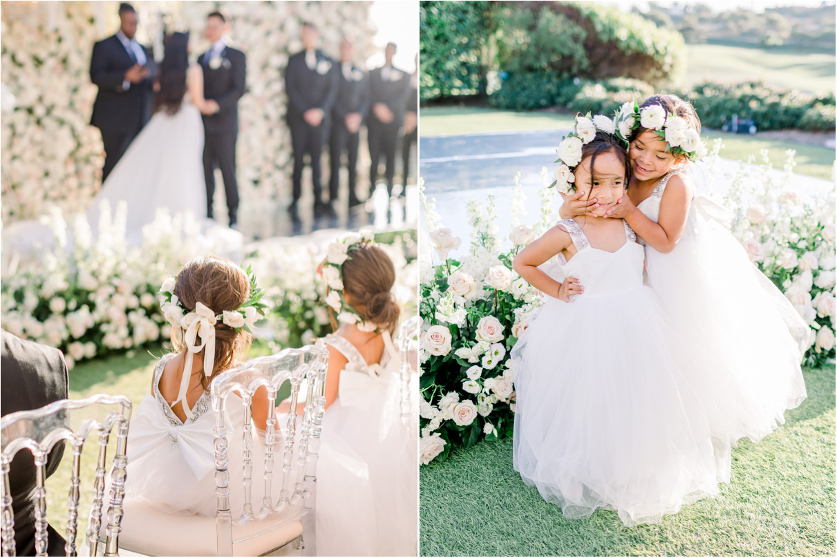 Two little girls in flower girl dresses and crowns watching their parents get married