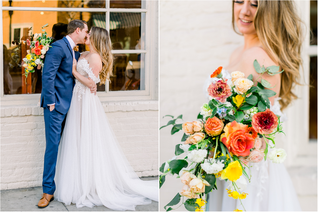 Wedding couple kissing outside white brick building holding large colorful bouquet