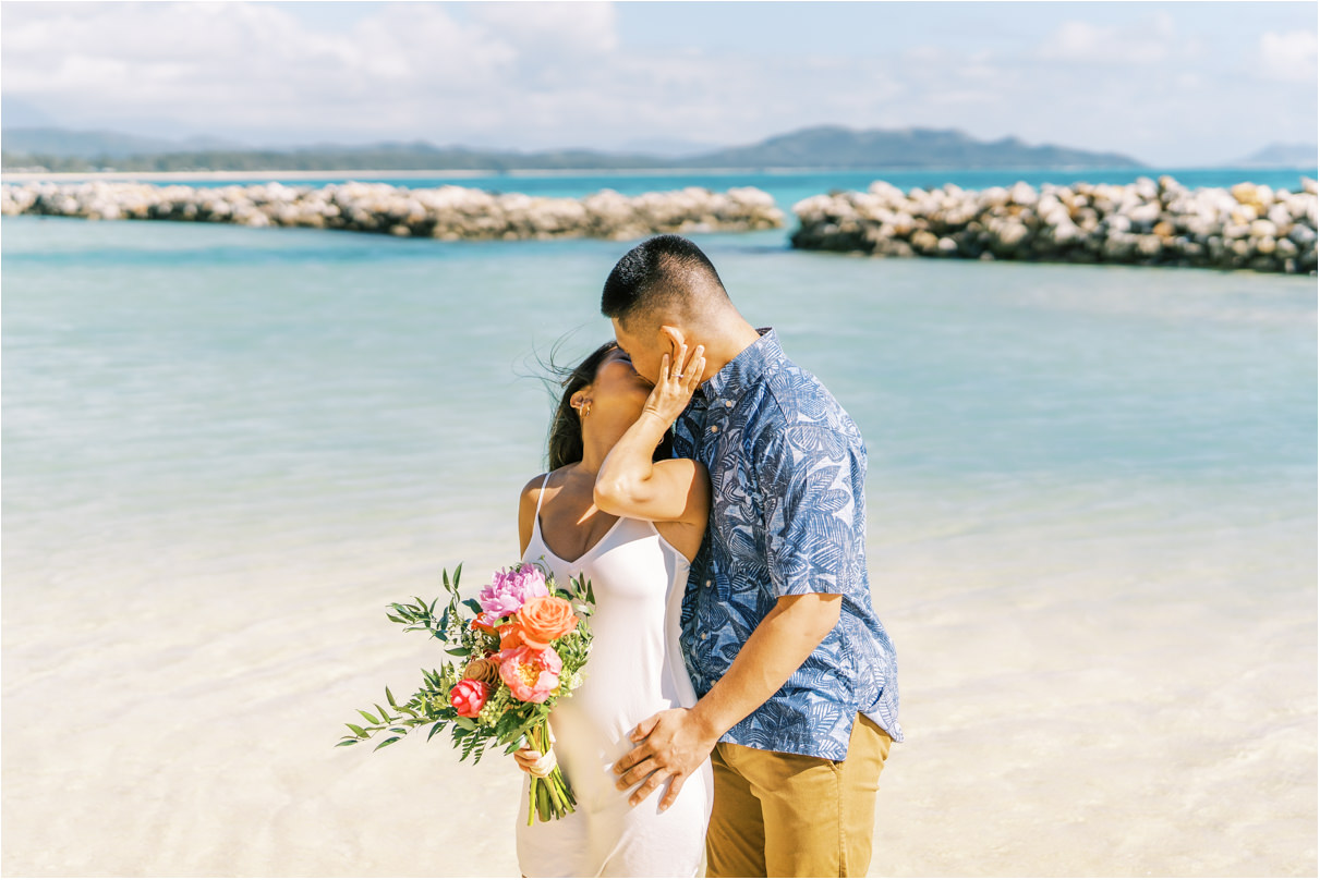 couple kissing at beach for engagement photos in hawaii