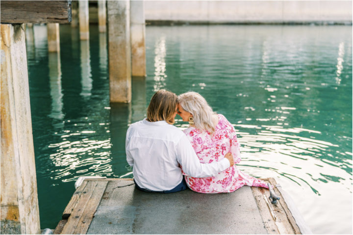 couple sitting on pier with heads together