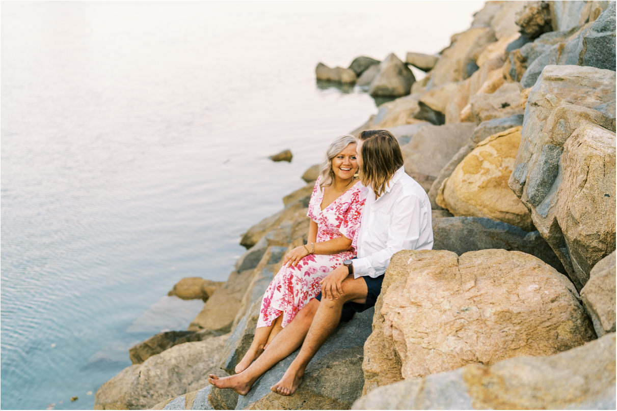 Couple sitting on rocks at Dana Point Harbor for engagement photos