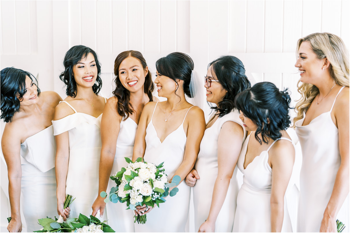 Bride laughing with her bridesmaids in white dresses