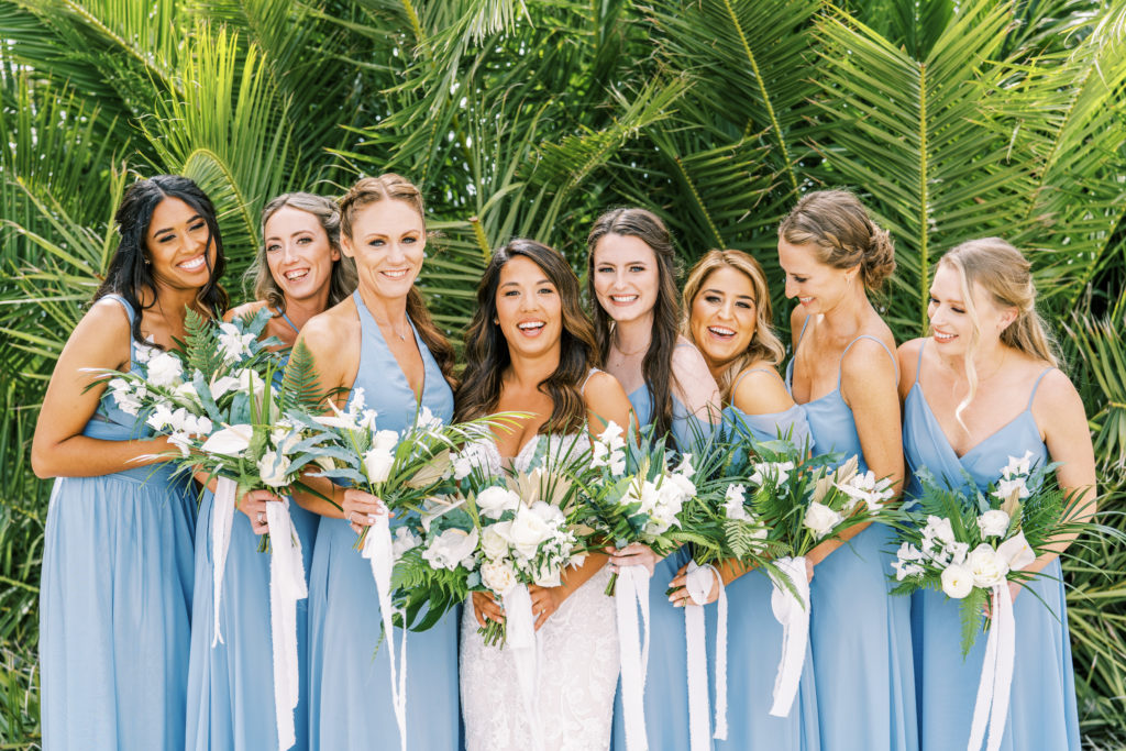 bride with bridesmaids holding flowers in blue dresses