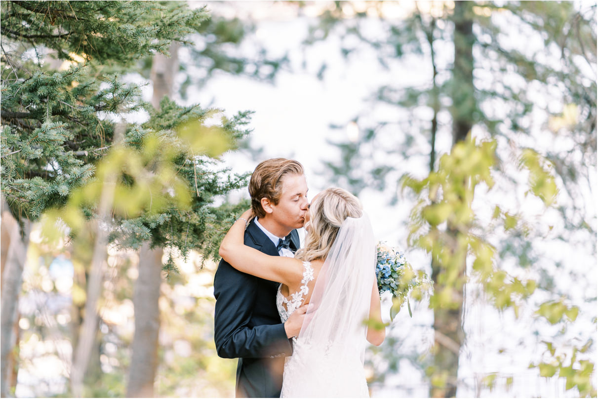 Bride and groom kissing amongst the trees