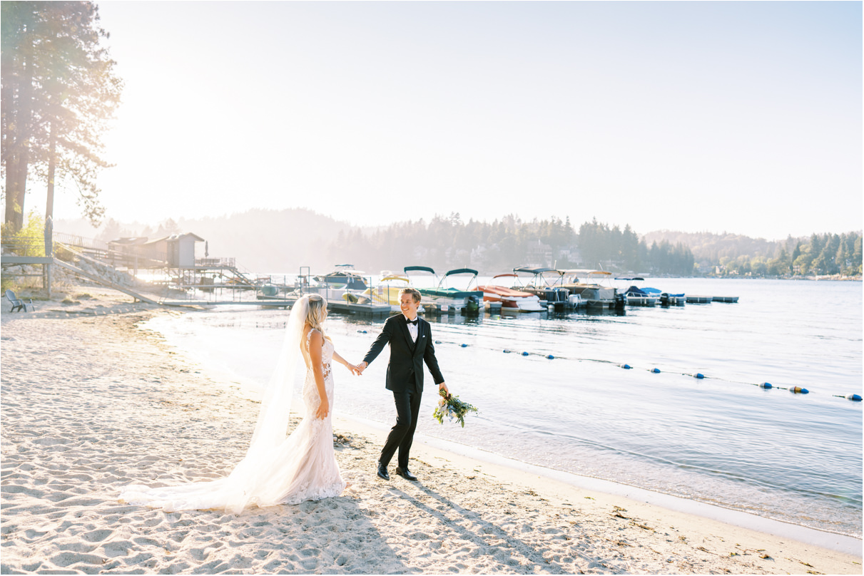 Bride and groom walking along sand at Lake Arrowhead