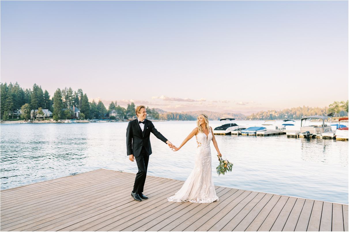 Bride and groom walking at sunset along dock on Lake Arrowhead